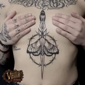 Tatuaje daga con mariposa entre el pecho