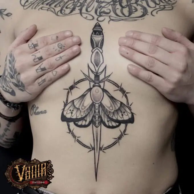 Tatuaje daga con mariposa entre el pecho