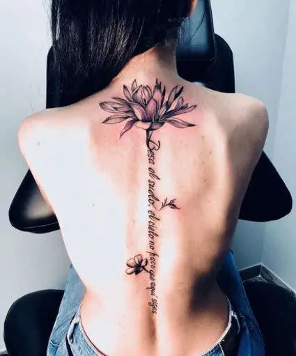 Tatuaje espalda flor de lis en la columna con frase, trabajo de Inkpulso Tattoo
