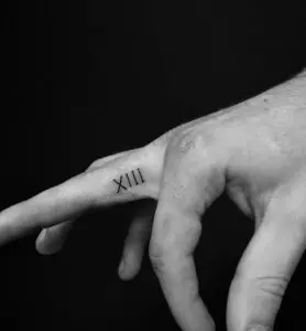 Tatuaje con número romanos en el dedo