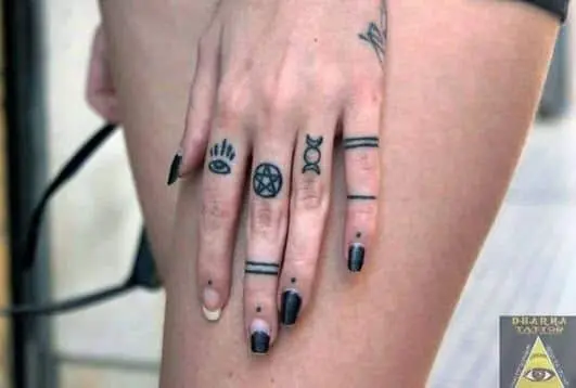 Tatuajes símbolos en los dedos de una mujer, trabajo de Dharma Tattoo