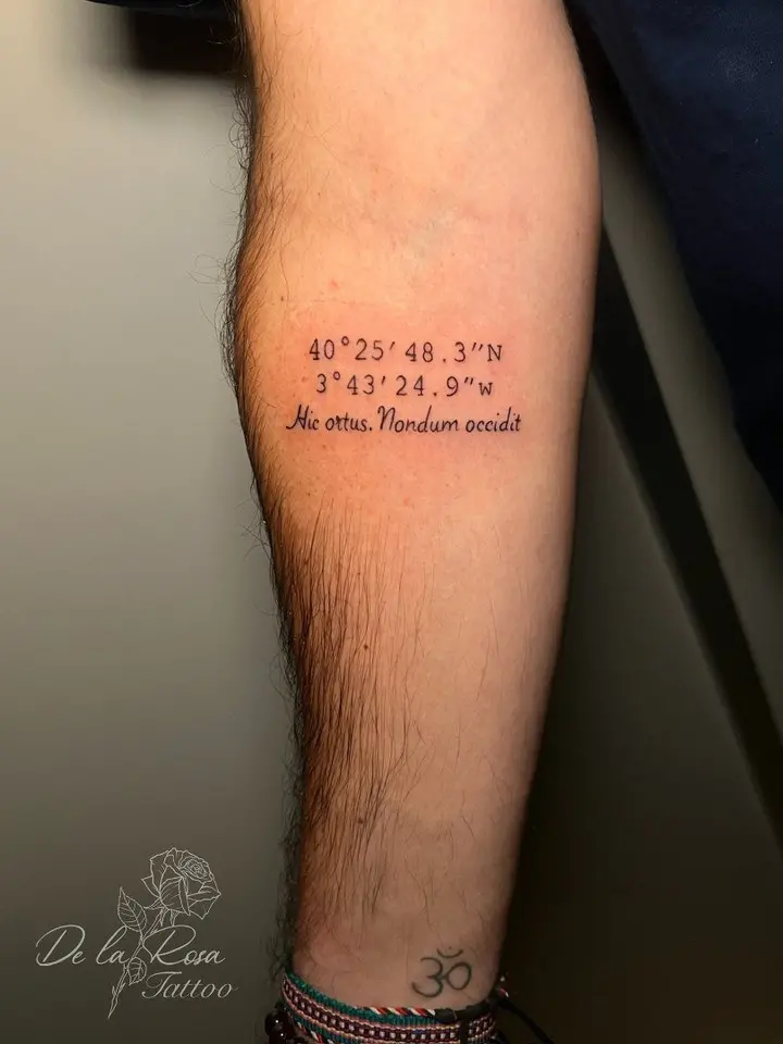 Coordenadas y frase en latín en el antebrazo